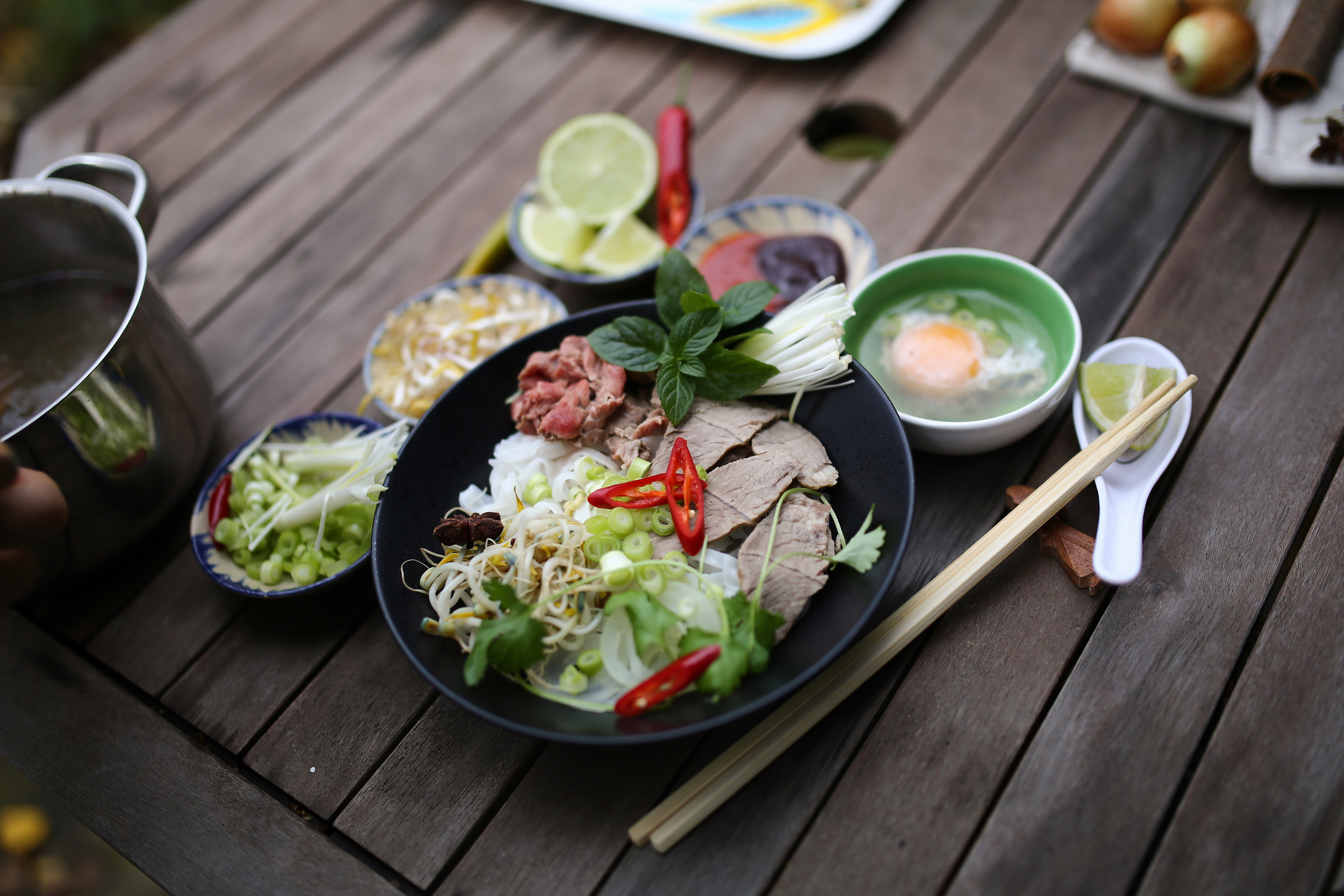 a bowl of food on a table with chopsticks and other utensils